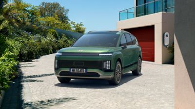 Il SUV elettrico Hyndai IONIQ 9 parcheggiato davanti a una casa.