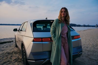 Ragazza guarda orizzonte appoggiata a IONIQ 5