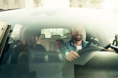 Innsyn gjennom frontruten inn i en Hyundai med en glad familie. Foto.