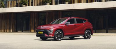 Zijaanzicht Hyundai KONA Electric N Line Business geparkeerd voor een appartementencomplex.