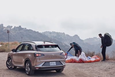 Deux parapentistes emballent leurs voilures à côté d’un véhicule à pile à combustible à l’hydrogène Hyundai NEXO.