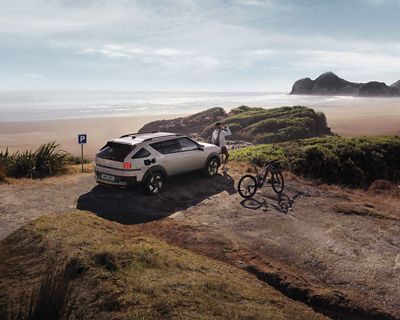 Hyundai NEXO stationné près des falaises et de la mer, avec un vélo électrique raccordé à sa prise V2L.