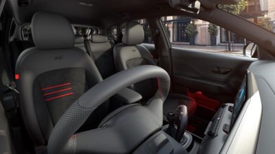 The sporty front seats of the KONA N Line with red accents and ambient lighting.