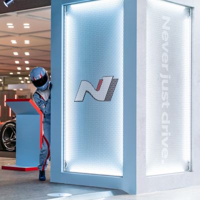 Hyundai N Man peeking around the corner at a motorshow.