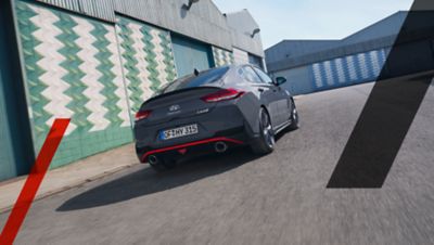 The Hyundai i30 Fastback N driving past airplane hangars.