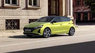 Hyundai new i20 in lucid lime parked on the side of the road in front of house.