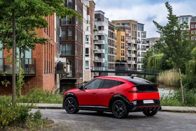 Driekwart achteraanzicht Hyundai IONIQ 3, met appartementen op de achtergrond.