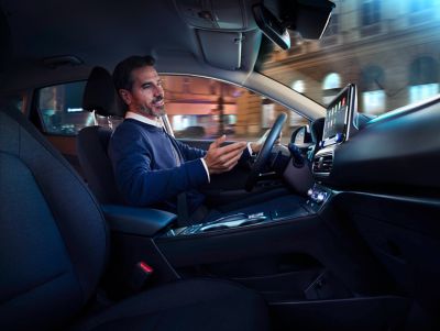 A man sitting behind the wheel of his Hyundai, talking.