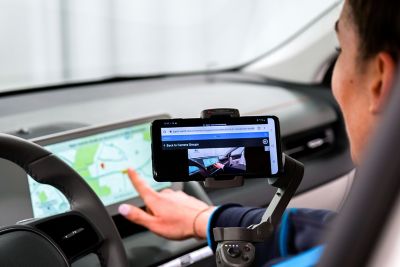 	 Eine Hyundai Online-Showroom Beraterin filmt einen Navigationsbildschirm und demonstriert seine Funktion.