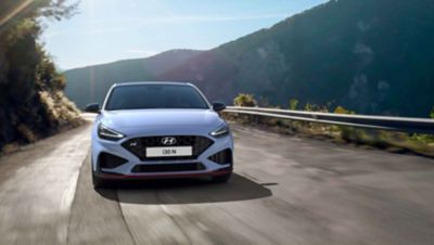 The Hyundai i30 N from the front in Performance Blue colour driving on a mountain road.