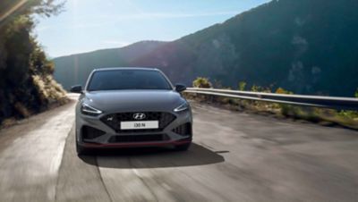 The Hyundai i30 N driving in a hilly set in the colour Shadow Grey.