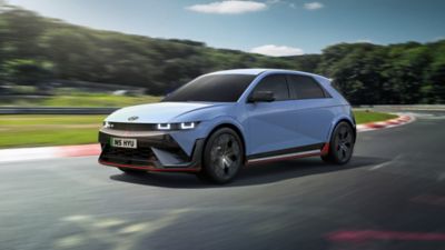 The all-electric Hyundai IONIQ 5 N driving on a race track with some trees in the background.