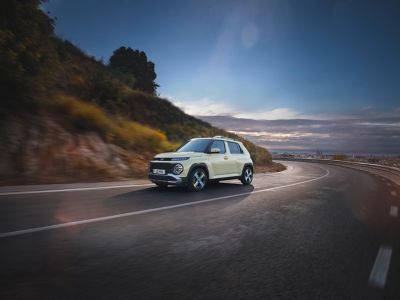 A woman standing next to the Hyundai INSTER small electric car.