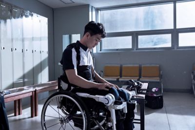 El atleta paralímpico Jun-beom Park sentado en su silla de ruedas en un vestuario.