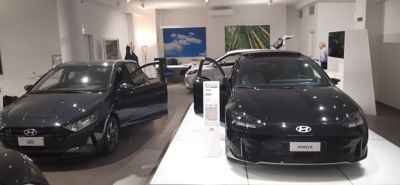 Interno dello showroom con in primo piano IONIQ 6 Nera a destra e a sinistra i20 nera