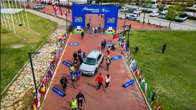 Şehirde cadde üzerinde koşan biri turuncu diğeri mavi ceketli iki koşucunun bulanık görünümü. 