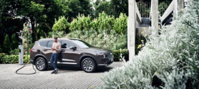 Ragazzo appoggiato a Hyundai SANTA FE Plug-in Hybrid in carica