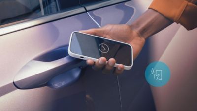 Close-up van een man die een smartphone gebruikt met Hyundai Digital Key 2 Touch om de autodeur te ontgrendelen.