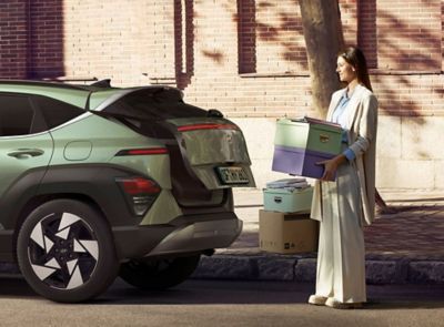 Žena s krabicemi stojící u nového Hyundai KONA.
