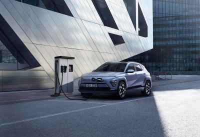 The all-new Hyundai KONA Electric parked in front of a modern building complex