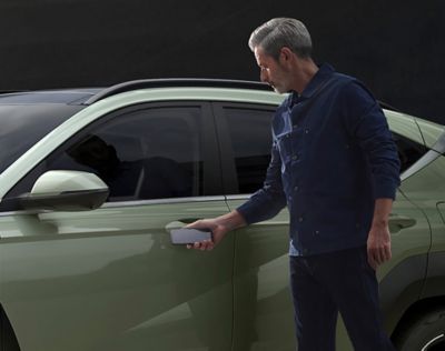 Een man benut de connectiviteit van de Hyundai KONA door de deur te openen met zijn smartphone.