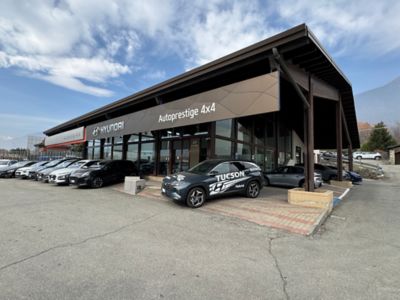 Esterno del capannone dello showroom, con davanti un TUCSON Hybrid blu
