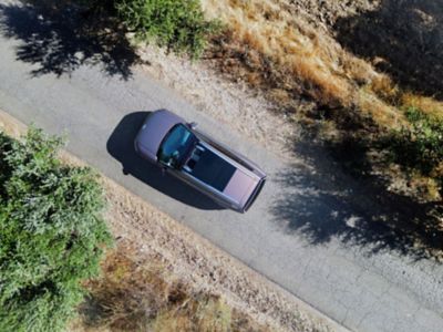 En bil kjørende på en landevei sett ovenifra. Foto.