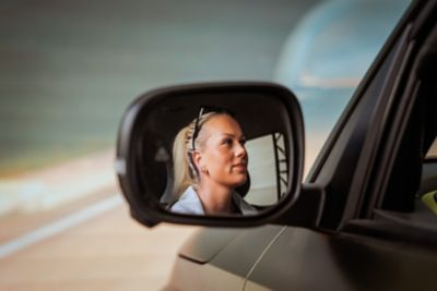 En jente som tester simulatoren ses i sidespeilet. Foto.