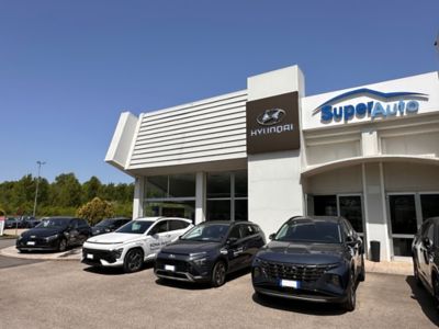 Esterno dello showroom con parcheggiate davanti Hyundai TUCSON Blu, KONA grigia e KONA Hybrid bianca