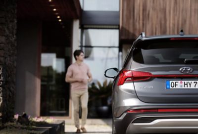 Nové sedmimístné SUV Hyundai Santa Fe Hybrid zezadu, zaparkované před domem.
