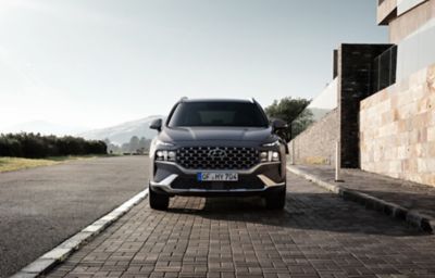 The new Hyundai Santa Fe Hybrid 7 seat SUV in grey parked on a city street.