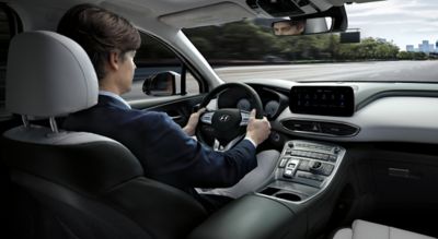 Interior view of the Hyundai Santa Fe Hybrid 7 seat SUV showing a man driving down the highway.