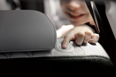 Interior view of the Hyundai Santa Fe Hybrid 7 seat SUV showing a child adjusting the headrest.