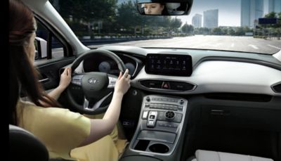 Imagen del interior del nuevo Hyundai SANTA FE Híbrido de 7 asientos con una mujer que conduce por la ciudad.