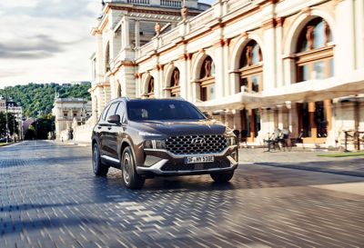 Nuevo Hyundai SANTA FE Híbrido Enchufable de 7 plazas circulando por la calle de una ciudad.