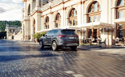 Nové 7místné SUV Hyundai Santa Fe Hybrid jedeoucí městem.
