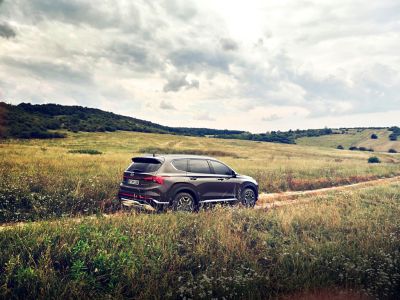 Nuova SANTA FE Plug-in Hybrid, il SUV a 7 posti di Hyundai mentre percorre una strada di campagna in collina