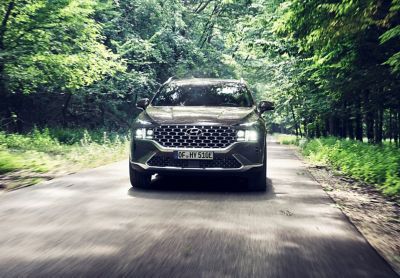 The Hyundai Santa Fe Plug-in Hybrid 7 seat SUV driving on a forest road.