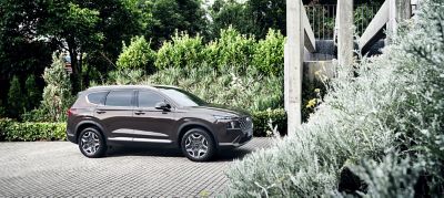 Nye Hyundai SANTA FE Plug-in Hybrid 7-seter SUV parkert foran et hus. Foto.