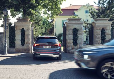 The Hyundai Santa Fe Plug-in Hybrid 7 seat SUV driving through an  entrance gate of a house.