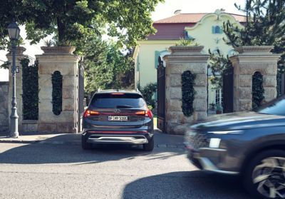 The Hyundai Santa Fe Plug-in Hybrid 7 seat SUV driving over a country lane in the hills.