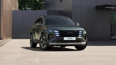 Side view of the new Hyundai BAYON in blue, with a concrete wall in the background.