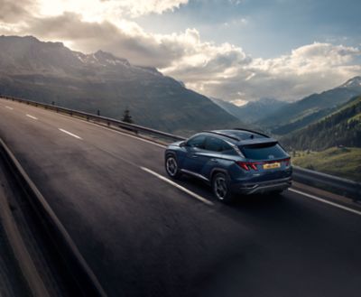 The Hyundai TUCSON Hybrid driving on a road. 