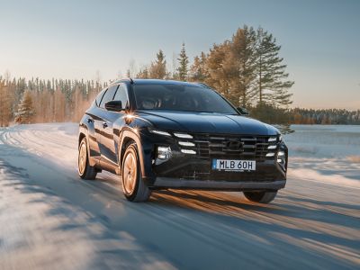 Hyundai TUCSON Plug-in Hybrid på en snötäckt väg i vinterlandskap.