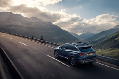 The Hyundai Tucson compact SUV driving through a mountain scenery.