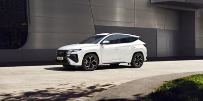 The Hyundai TUCSON Plug-in Hybrid parked in the street and a woman is standing in front of it.