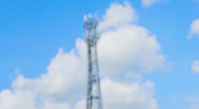 Telefonmast mot blå himmel og skyer. Foto