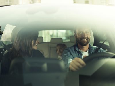 Looking inside a Hyundai through the windshield, a family in the car is looking happy.