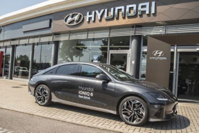 Hyundai IONIQ grigio metallizzato vista di lato fuori davanti allo showroom