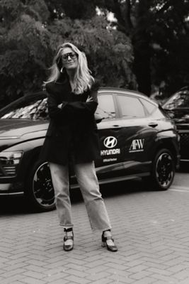 Danie Bles, CEO Amsterdam Fashion Week, met op achtergrond een Hyundai KONA Electric.